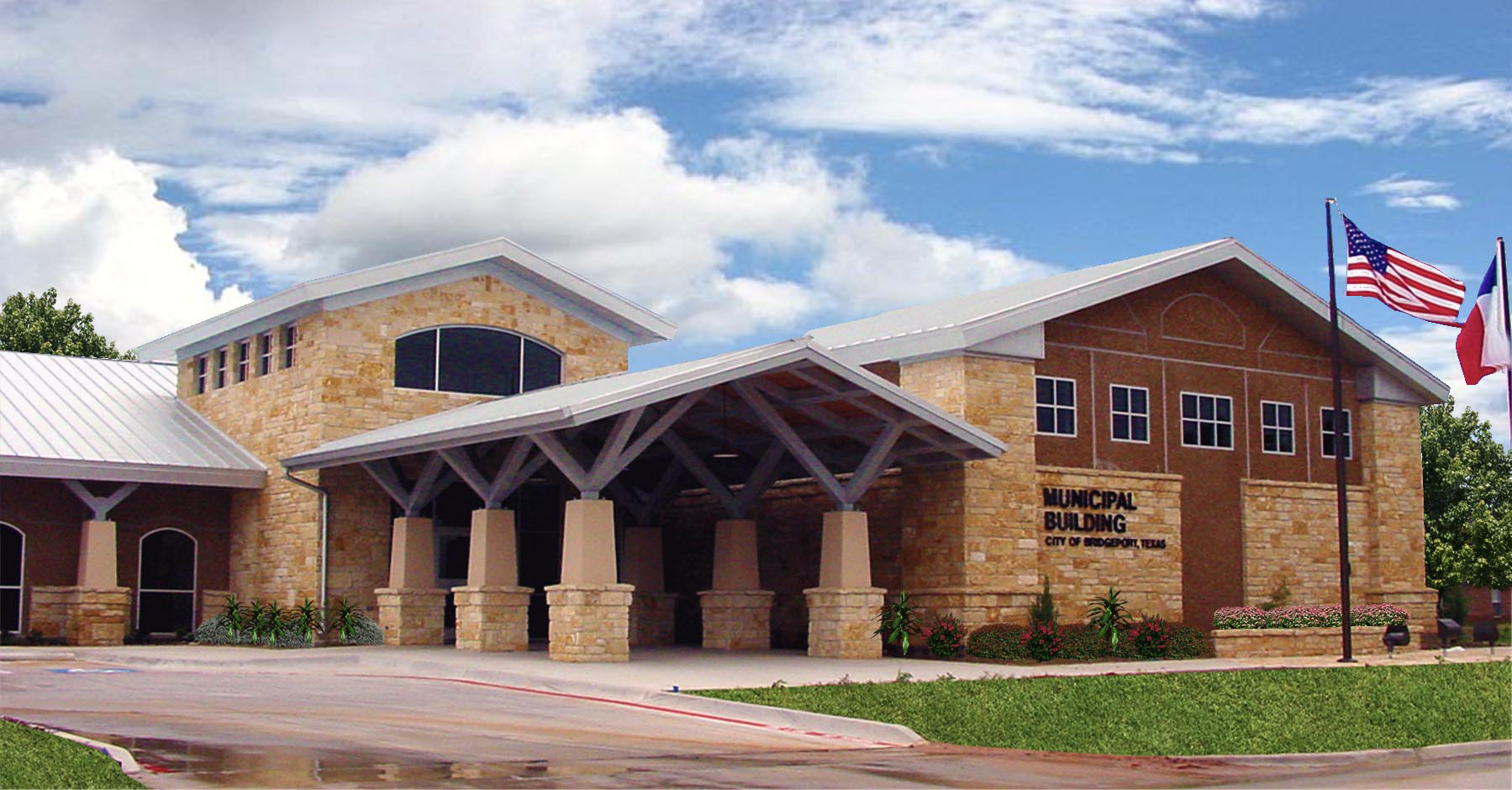 Front view of the Municipal Building in Murphy, Texas, featuring a stone facade, metal roof, and a covered entrance supported by stone columns. Two flagpoles stand in front, flying the American and Texas state flags. The sky is partly cloudy, and the building is surrounded by greenery.
